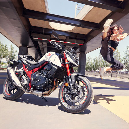 Tanečnice skákající ve vzduchu vedle modelu Honda CB750 Hornet.