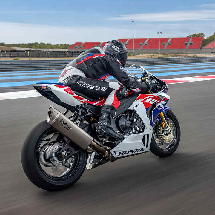 Zadní tříčtvrtinový pohled na motocykl Honda CBR1000RR-R Fireblade s jezdcem na závodní dráze